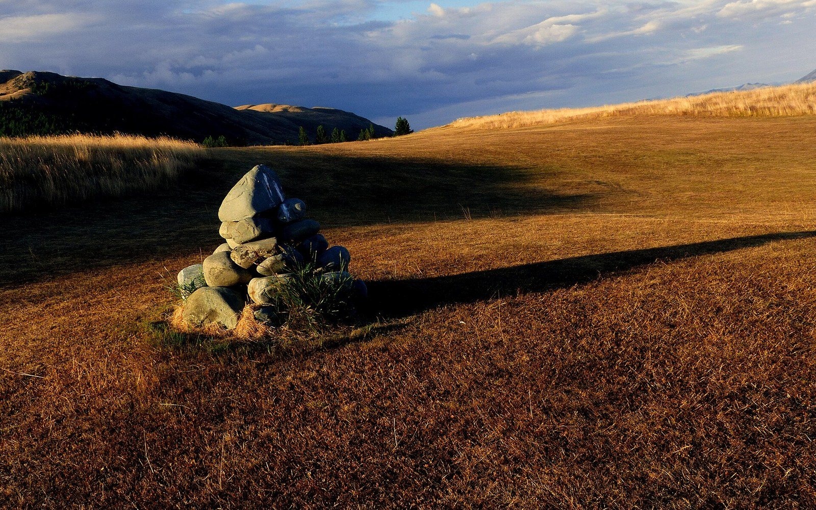 A large stone cairn on bare ground in flat cloud