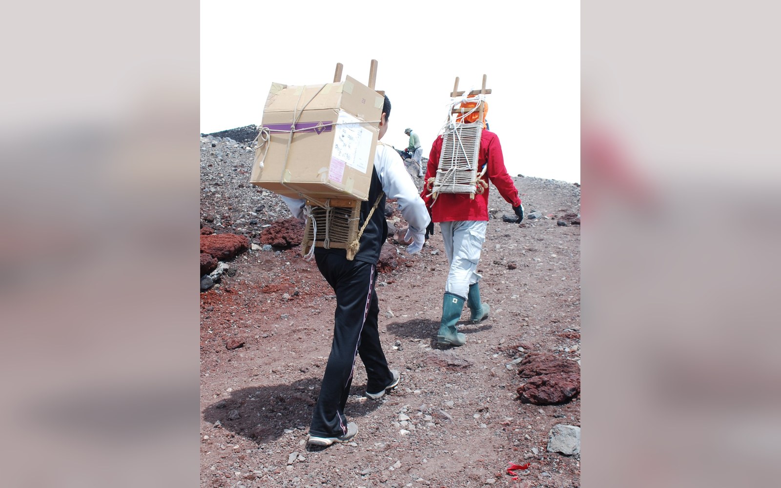 An external-frame pack propped against granite, hard sun